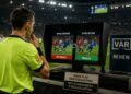 VAR referee reviewing the same football play to demonstrate how algorithmic penalties can be reversed after a new evaluation of existing signals.